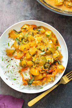 a white plate topped with rice and veggies next to a bowl of curry