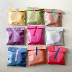 six different colored paper bags with some stickers on them and one has a note pinned to it