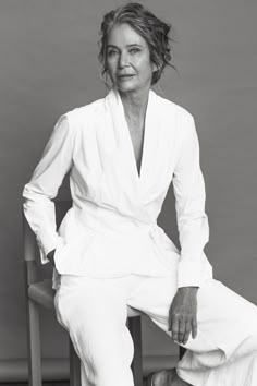 a black and white photo of a woman sitting in a chair with her hands on her hips