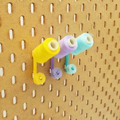 three spools of thread are hanging on a peg board with holes in it