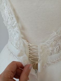 a woman's hand is touching the back of a wedding dress with beading on it