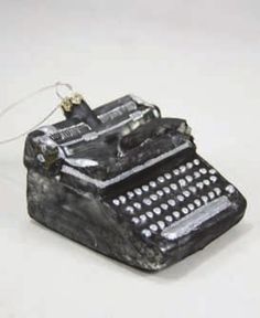 an old fashioned typewriter ornament on a white surface with a string attached to it