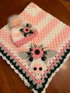 a crocheted blanket and hat on top of a wooden floor