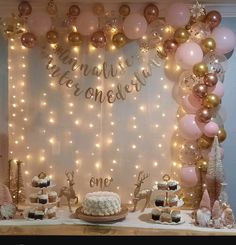 a table topped with cakes and desserts covered in pink, gold and white balloons