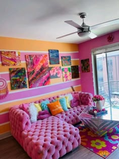 a living room filled with pink couches and colorful paintings on the wall above them