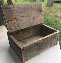 an old wooden box sitting on top of a white table in front of some trees