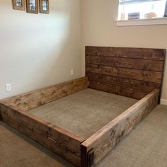 a bed frame made out of wood in a room with carpeted flooring and two framed pictures on the wall