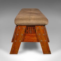 an old wooden stool with a seat cushion