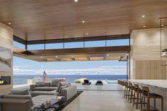 a living room filled with furniture next to an open kitchen and dining area near the ocean