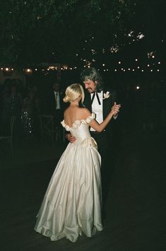 a man in a tuxedo standing next to a woman