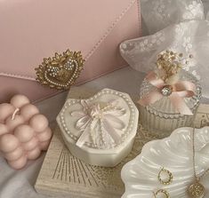 an assortment of jewelry is displayed on a white tablecloth with pink and gold accessories