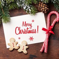 two gingerbreads are next to a christmas card on a table with candy canes