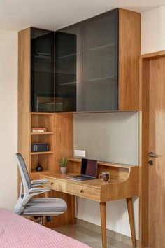 a wooden desk with a laptop on top of it next to a chair and bookshelf