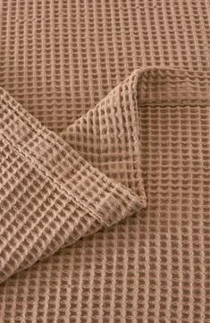 a brown blanket is folded on top of a bed