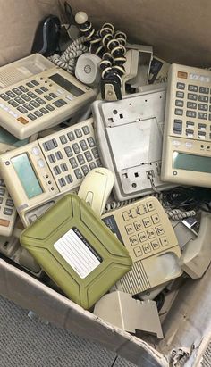 an open box filled with old telephones and other electronic devices, including two phones