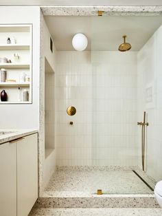 a white bathroom with gold fixtures and marble counter tops, along with a walk in shower