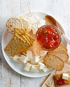 a white plate topped with crackers and cheese next to a bowl of ketchup