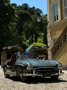 an old classic car parked in front of a building with stairs leading up to it