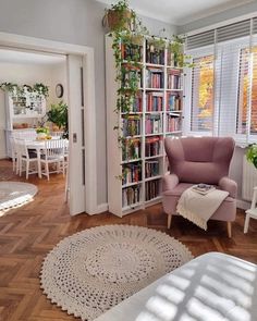 a living room filled with lots of furniture and bookshelves next to a window