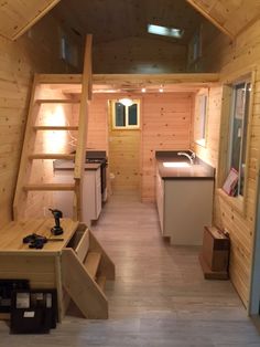 the interior of a tiny cabin with stairs leading up to the kitchen and living room