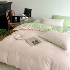 a bed with white sheets and pillows on top of it next to a table filled with books