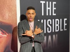 a man making a funny face while standing in front of a poster with his arms crossed