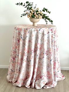 a vase with flowers sitting on top of a table covered in a pink floral fabric