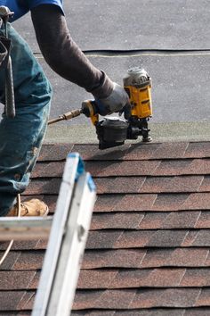 a man using a power drill to fix a shingled roof