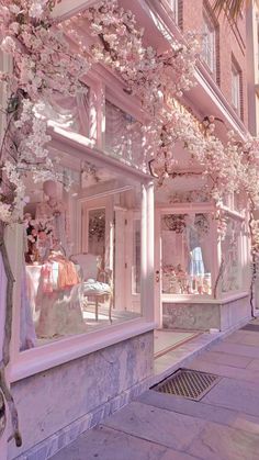 a storefront with pink flowers on the outside and in the front window is a mannequin