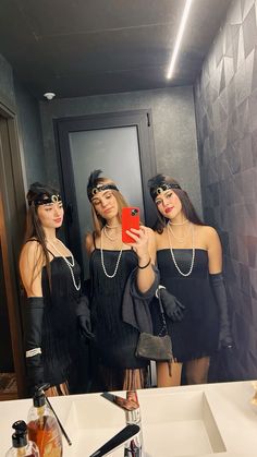 three women dressed up in flappers and garb are taking a selfie in the mirror