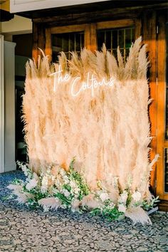 the reception backdrop is made up of feathers and greenery, along with white flowers