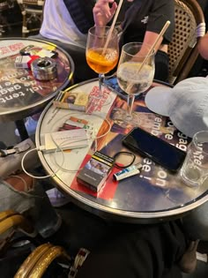 two people sitting at a table with drinks and cell phones on it, one holding a straw