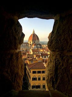 the view from inside an old building looking down on buildings and dome tops in italy