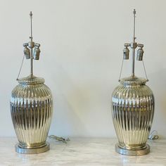 two silver vases sitting next to each other on a white counter top with wires attached to them