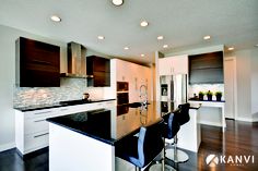 a kitchen with an island and bar stools next to the counter top in front of it