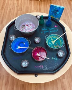 a black tray with bowls and spoons on it that have different colored liquids in them