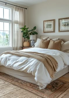 a bedroom with a large bed and two plants on the side of the window sill