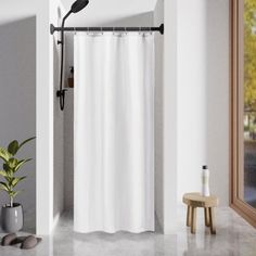 a white shower curtain in a bathroom next to a potted plant