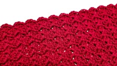 a red crocheted cloth is shown on a white surface with the corner stitched in