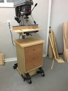 a drill press machine sitting on top of a wooden cabinet