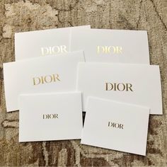 four white cards with gold foil on them sitting on top of a carpeted floor