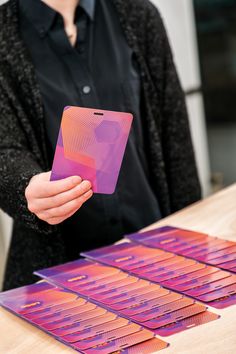 a person holding up a cell phone in front of some purple and pink designs on a table