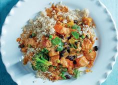 a white plate topped with rice and veggies next to a blue table cloth