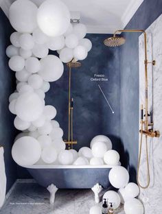 a bathtub with balloons floating from the ceiling in a blue and white bathroom area