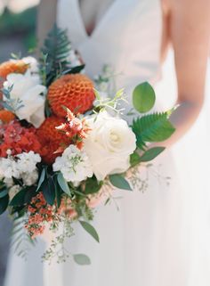 a bridal holding a bouquet of flowers and greenery