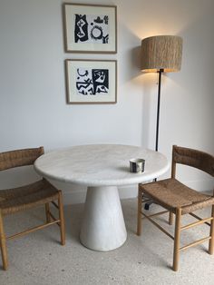 a white table and two chairs in a room with pictures on the wall behind it