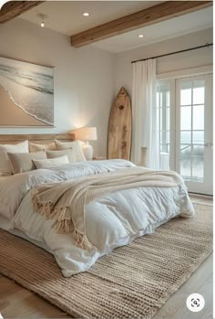 a bedroom with a surfboard on the wall next to it and a bed that has white linens