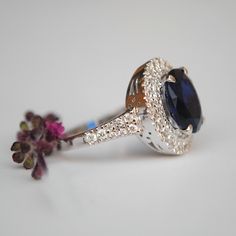 "A ring style of the royalties, this design flaunts an oval synthetic blue stone, surrounded by 0.66cts of double natural diamond halo. Crafted in solid 14k gold, the shank tapers and has diamonds enhancing the overall look. * Center Stone : Blue Sapphire Imitation (for natural, please message) * Shape : Oval (10x8 mm) * Halo Gemstones : Natural Genuine Diamonds * Diamond Wt. : 0.66 Cts * Color/Clarity : H-I, Vs-Si * Gold - 14kt, 5.9 gms solid white gold (approx) If you like this ring, please pr Luxury Rings With Center Stone Of Lab-created Sapphire, Luxury Rings With Lab-created Sapphire Center Stone, Elegant Halo Ring With Round Stone For Formal Occasions, Luxury Lab-created Sapphire Gemstone Ring, Luxury Sapphire Ring With Round Stone, Luxury Oval Tanzanite Diamond Ring, Luxury Rings With Lab-created Sapphire And Prong Setting, Luxury Sapphire Halo Ring For Formal Occasions, Luxury Lab-created Sapphire Ring For Formal Occasions