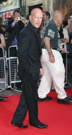 a man in black suit and white pants walking on red carpet