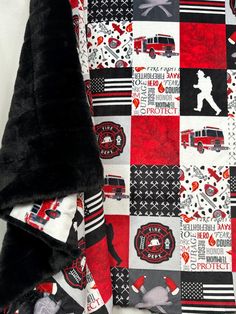 a blanket with firetrucks on it is laying next to a black teddy bear